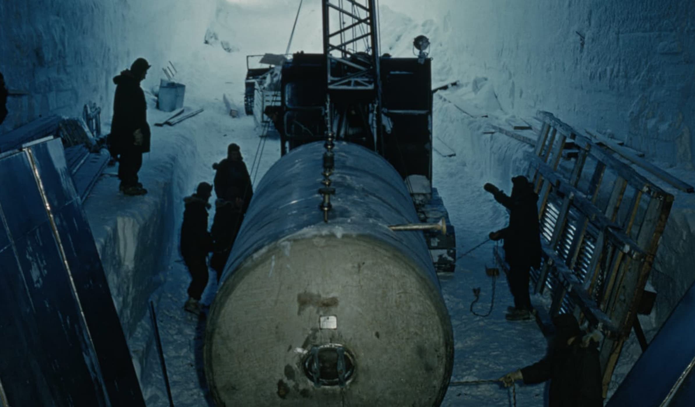 Six men inside a deep tunnel carved into the Arctic landscape, handling a substantial piece of nuclear equipment.