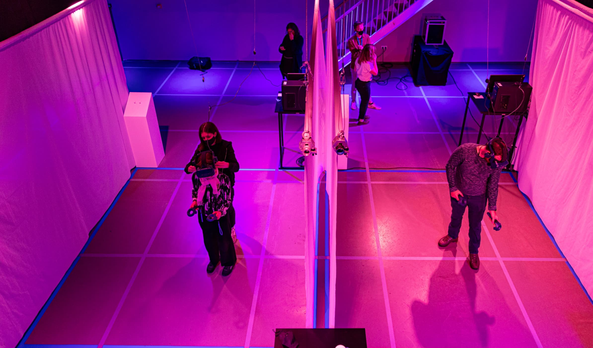 two people in a virtual reality exhibition space, eeach with a VR headset on xperiencing Camp Century while wearing virtual reality headsets.