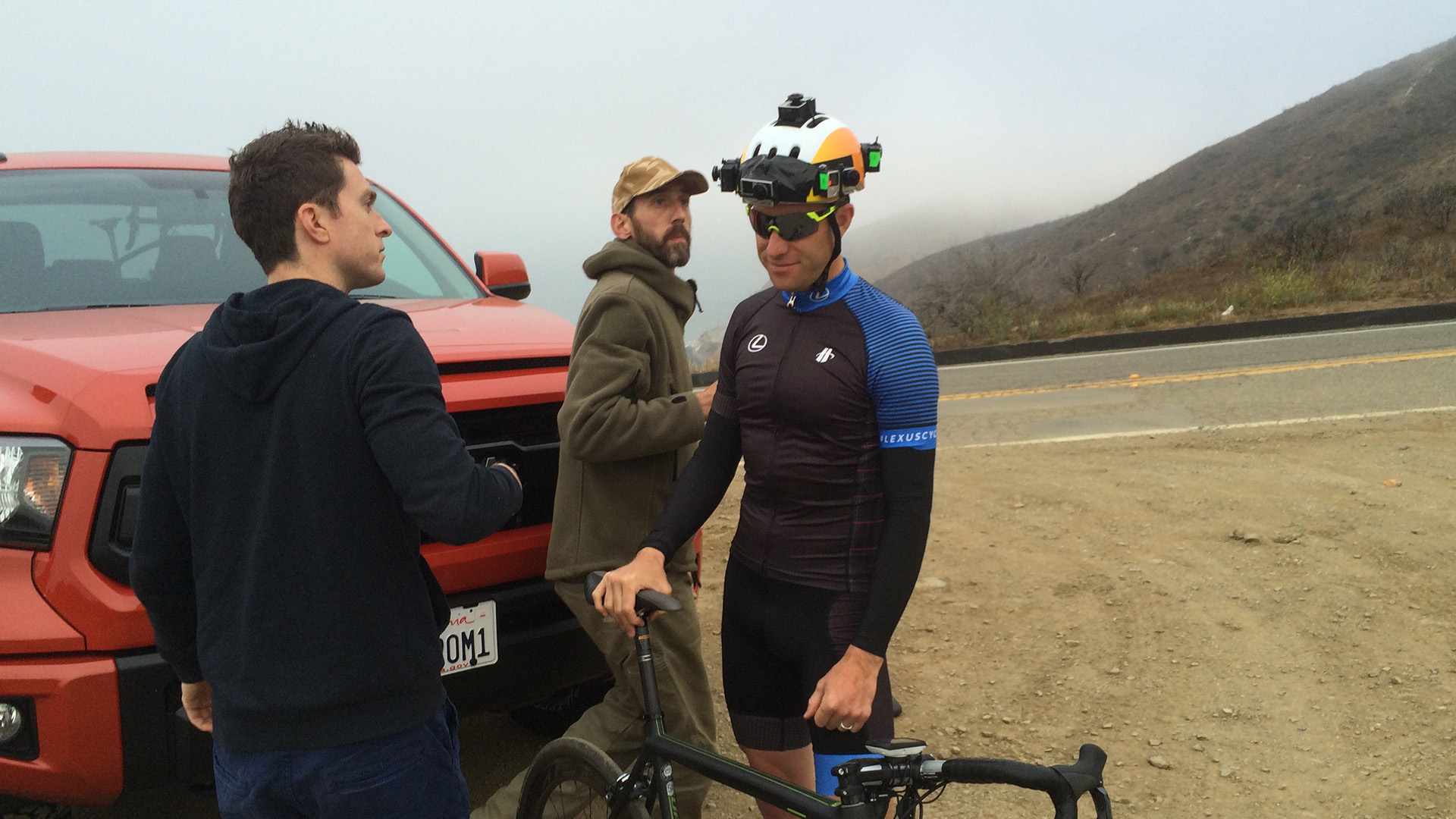Behind the scenes on the Elevate shoot: the film crew briefs cyclist Christian Vande Velde, who wears a custom camera rig on his helmet, on a misty Malibu roadside.
