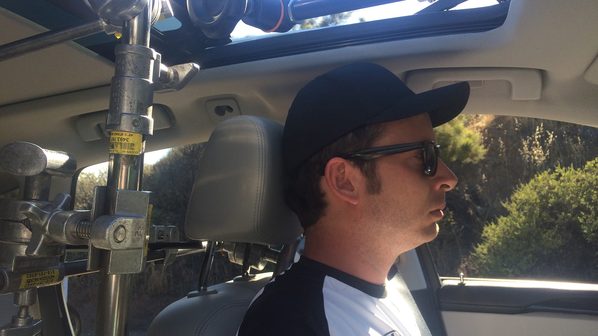 Behind the scenes on the Elevate shoot: a crew member inside a chase vehicle sits beside a complex camera rig mount, monitoring the camera setup.
