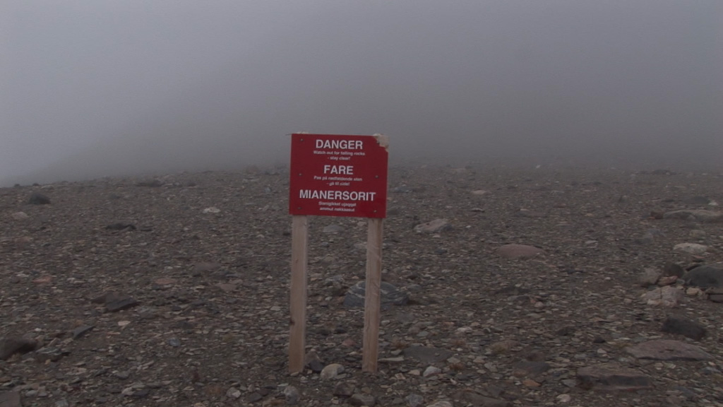 A screenshot of a red danger warning sign positioned in a foggy landscape