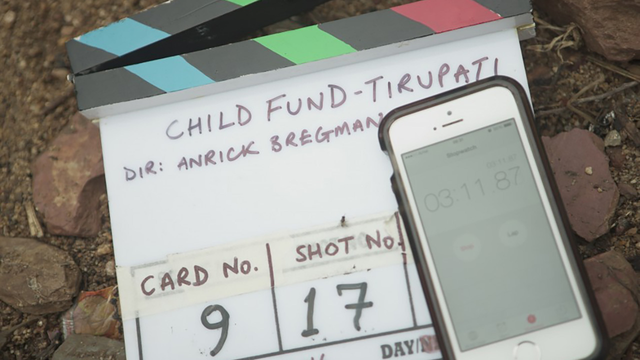 THE RETURN: A clapperboard reading Child Fund - Tirupati, Dir: Anrick Bregman, resting on rocky ground beside a phone stopwatch.