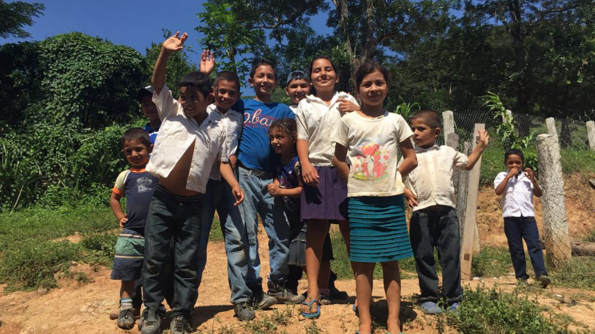 WATER: A group of children in a rural Honduran village wave and smile for the camera.